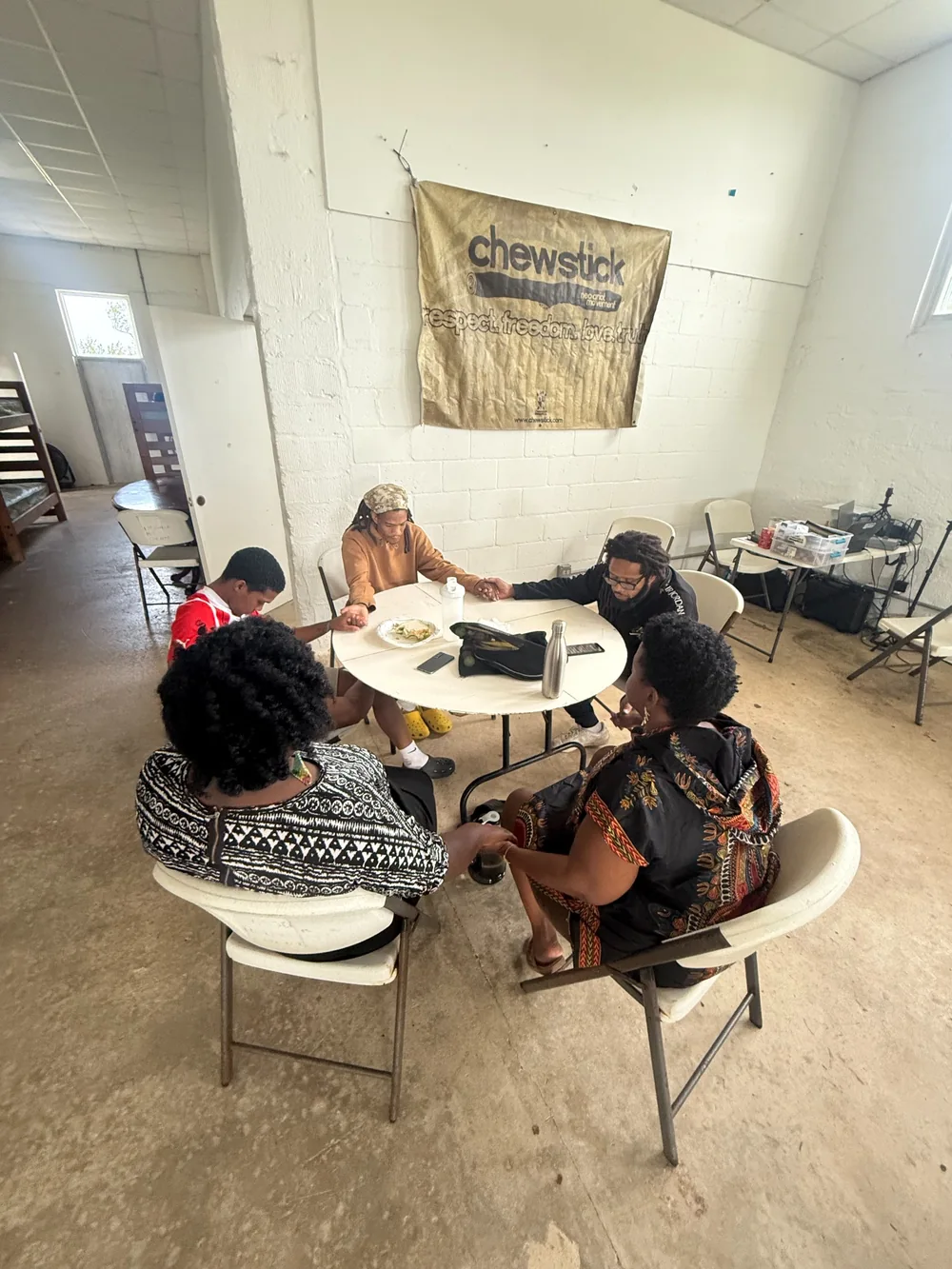 A small group exchanging ideas around a table beneath a Chewstick banner